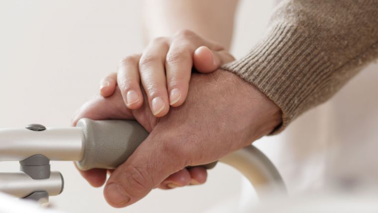 Young person's hand over older person's hand