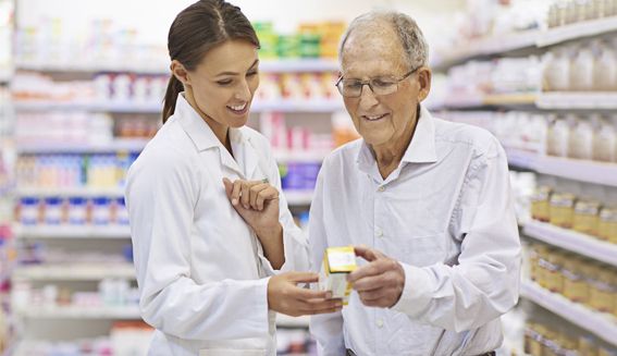 Pharmacist showing medication to elderly male customer