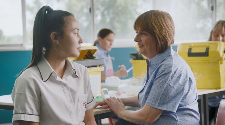 Image of nurse and student receiving a vaccination