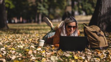 A young woman is working on her laptop in a park