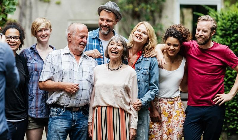 Large family group, with older couple at the centre, having a photo taken in the garden.
