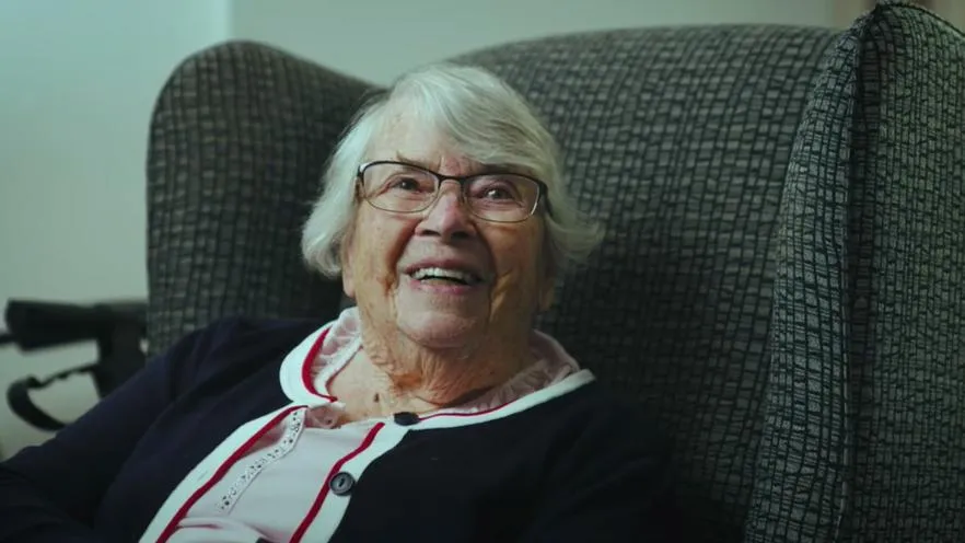 older woman smiling sitting armchair
