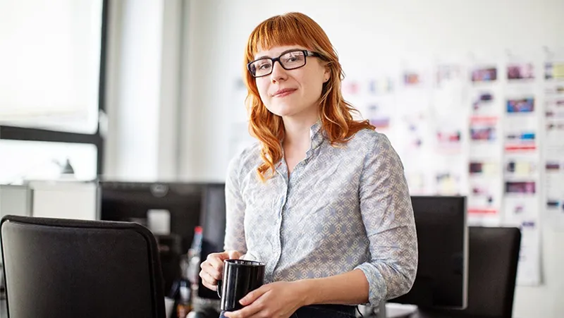 Woman holding a mug in front of chairs in a meeting room