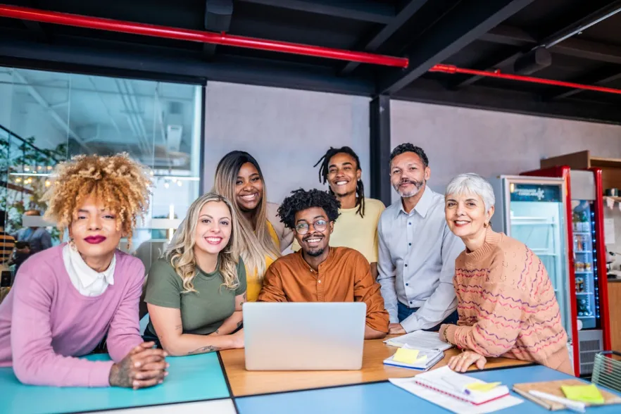 Photographic image of a group of people sitting around a laptop
