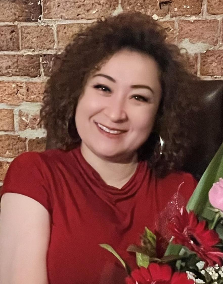 Image of Roxanne who is an aged care volunteer. Roxanne has brown curly hair and is wearing a red shirt