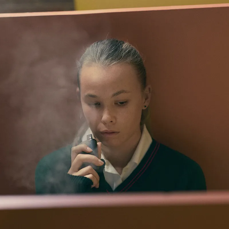 Image of girl wearing a school uniform smoking a vape