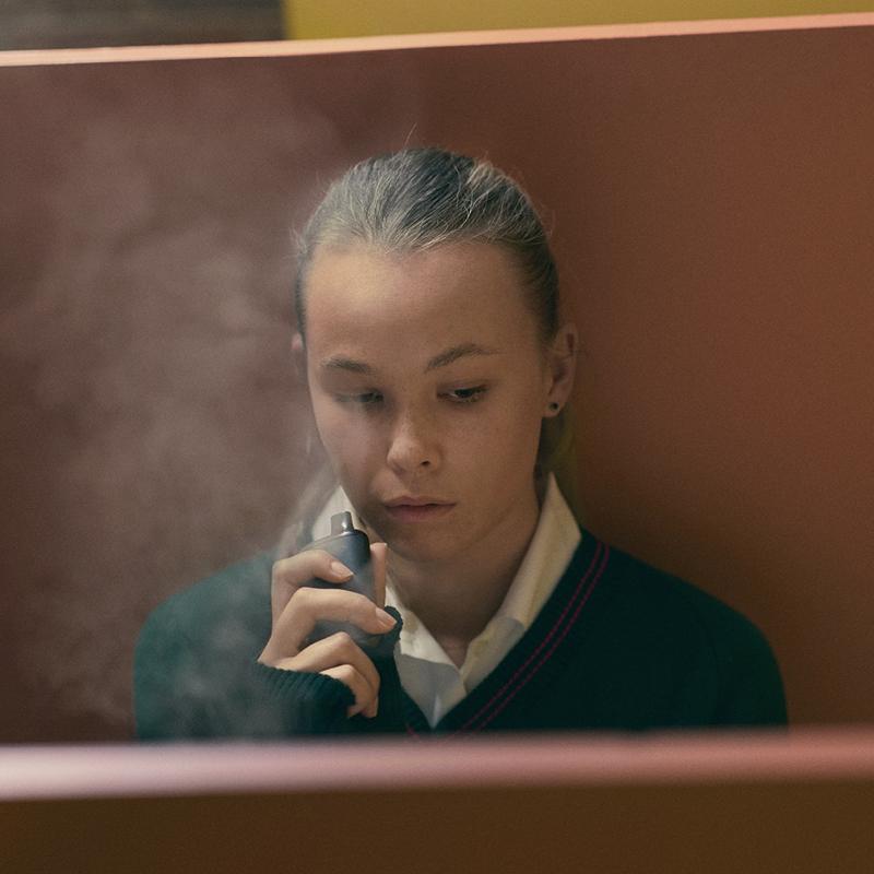 Image of girl wearing a school uniform smoking a vape