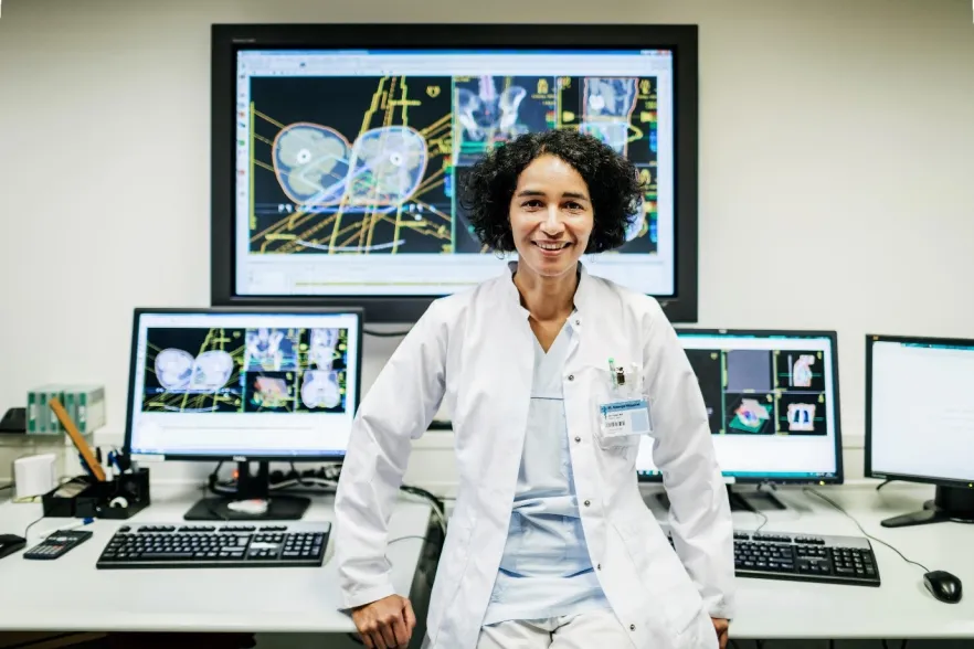Female scientist stand in front of various screens