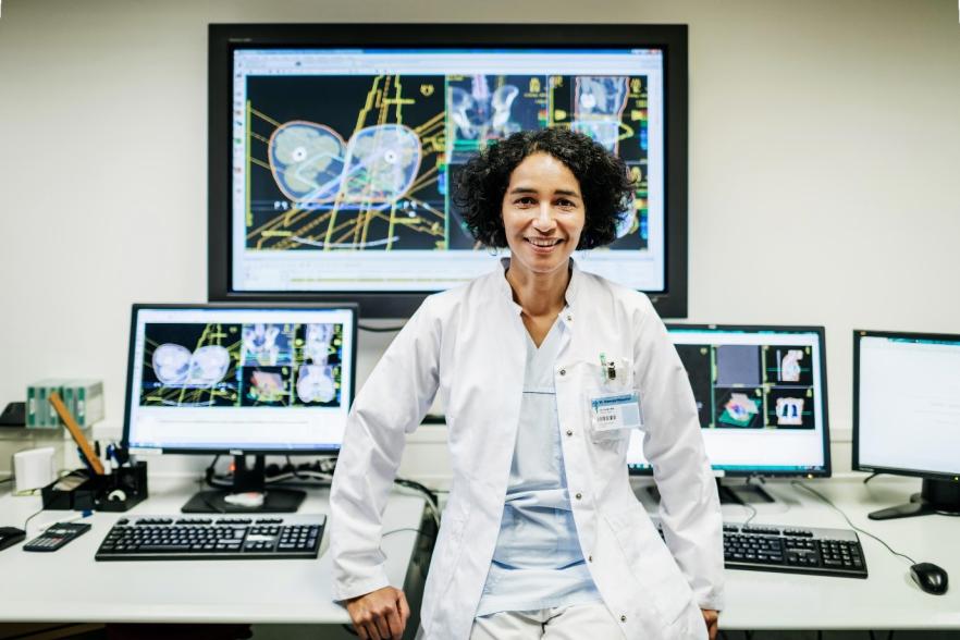 Female scientist stand in front of various screens