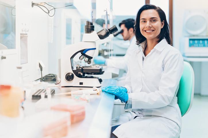 Researcher sitting at a workstation with a microscope