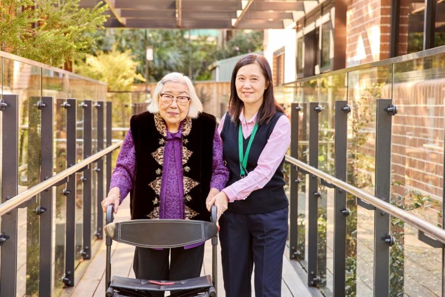 Elderly lady with walker and carer