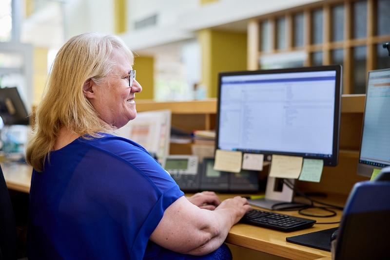 Female office worker typing and viewing desktop screens
