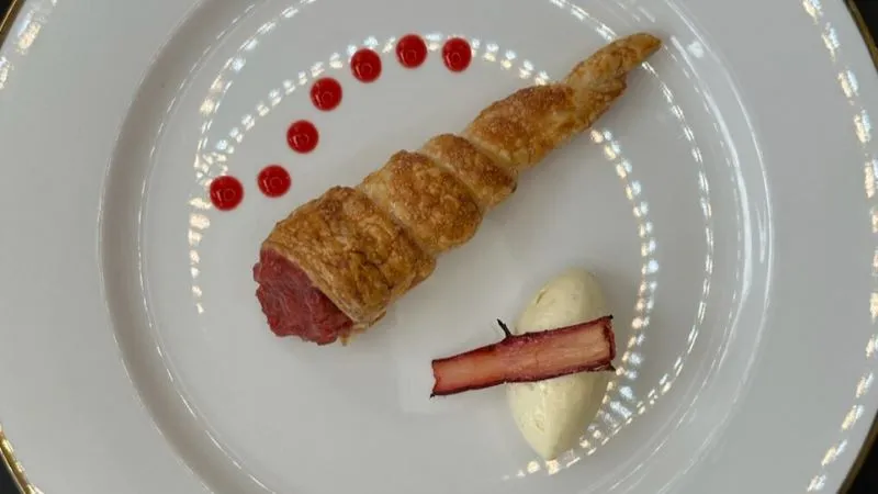 Dessert presented with care at BaptistCare Orana, a pastry with dots of coulis on the plate next to a roll of cream and a piece of rhubarb