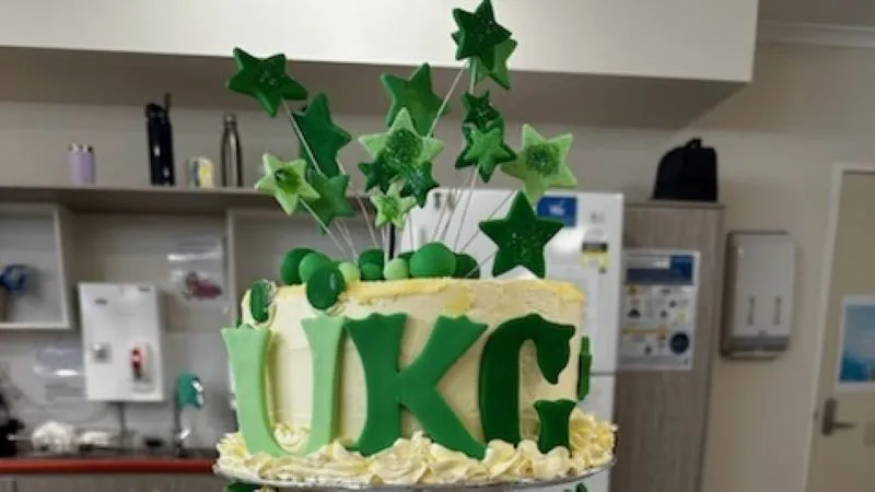 Elaborate birthday cake with the initals UKG spelled out in green letters, with green stars coming out of the top. Birthdays and other occasions are celebrated at BaptistCare Orana.