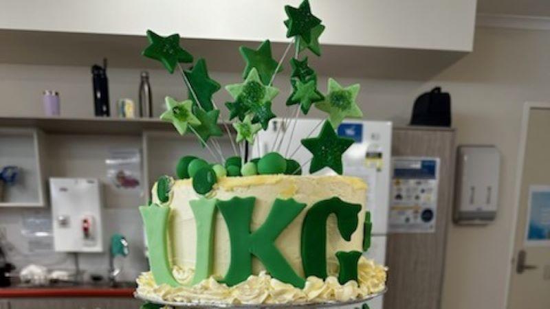Elaborate birthday cake with the initals UKG spelled out in green letters, with green stars coming out of the top. Birthdays and other occasions are celebrated at BaptistCare Orana.