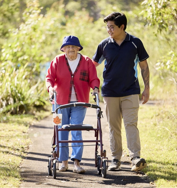 Elderly women walking with help from a carer