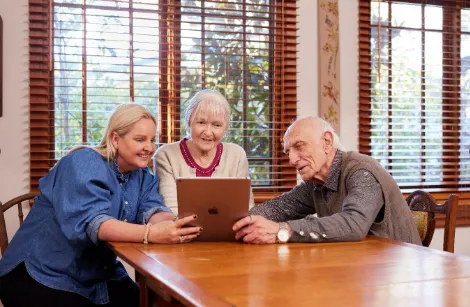 3 people at a dining table looking at a tablet together