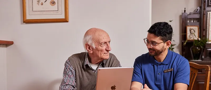 Photograph of an elderly male talking to a male carer