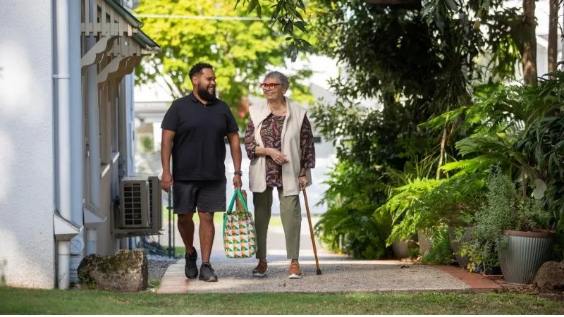 Elderly women walking with a male carer