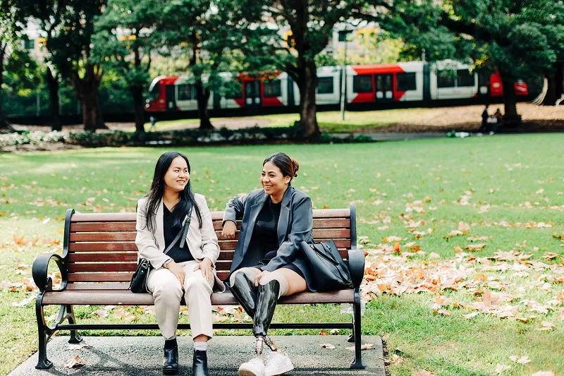 two_young_ethic_women_sitting_and_talking_on_a_park_bench