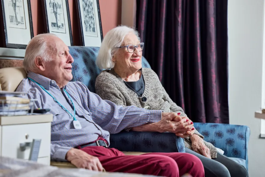 Elderly couple sitting together holding hands