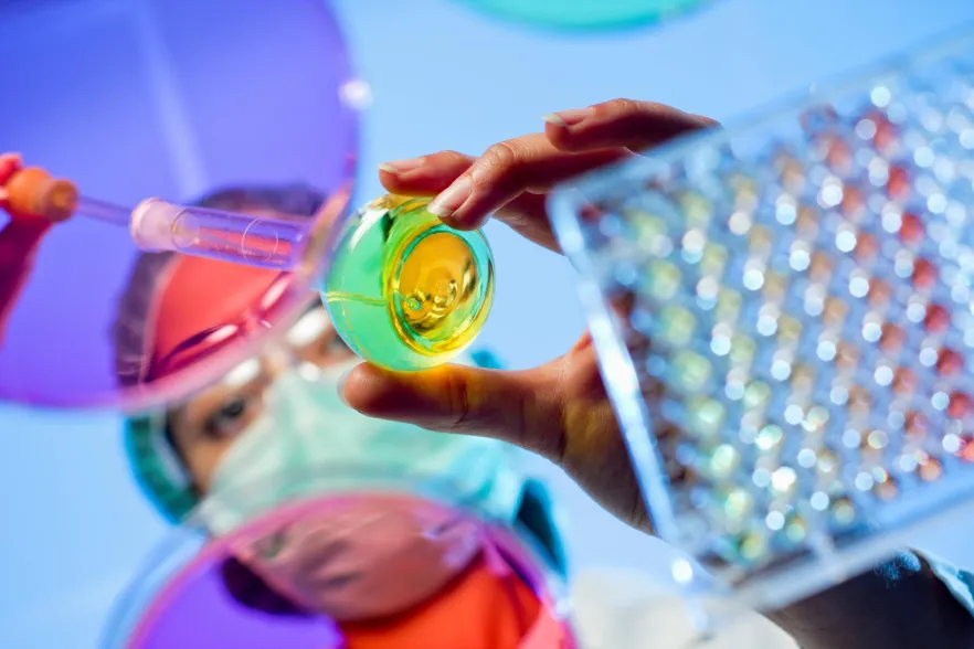 Image of female Laboratory technician added liquid to a vile. This view is from under a glass desk