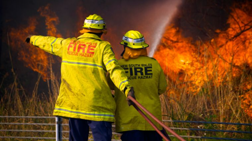 Two firefighter and bushfire flames