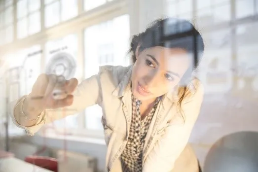 Woman writing on a clear whiteboard