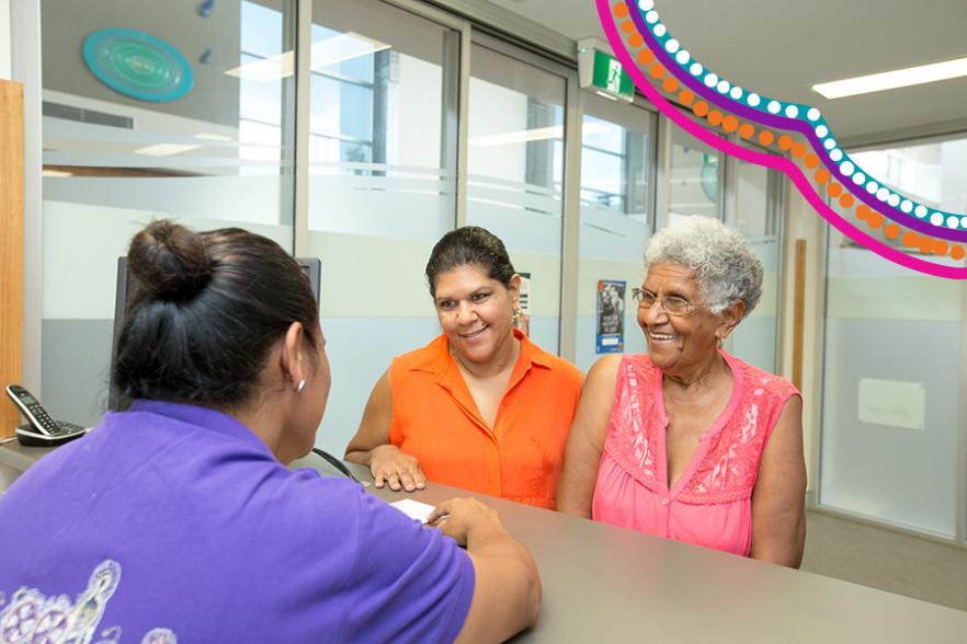 Two Aboriginal and Torres Strait Islander women standing at counter being served by a third woman