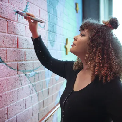 Female Aboriginal artist painting on a wall
