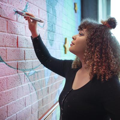 Female Aboriginal artist painting on a wall