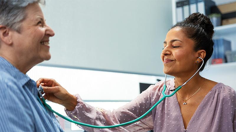 Female doctor using a stethoscope on a male patient