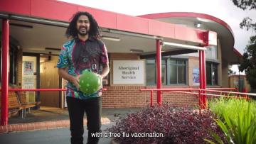 First Nations man smiling and holding a soccer ball outside an aboribinal health service