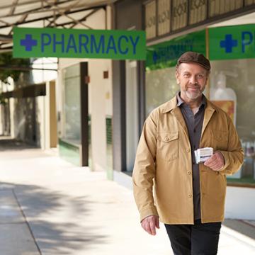 Campaign tile of man holding medicine outside of pharmacy