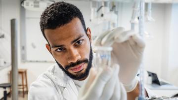 Man with a beard in a laboratory setting looking at a sample close up