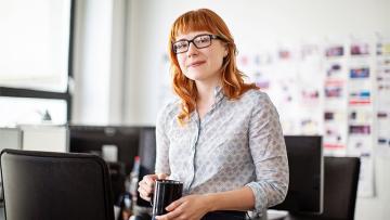 Woman holding a mug in front of chairs in a meeting room