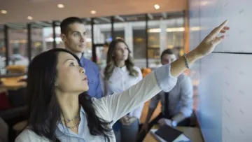 Woman pointing at whiteboard with group