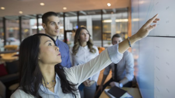 Woman pointing at whiteboard with group