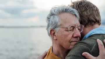 Cover image of 2 people hugging near a body of water