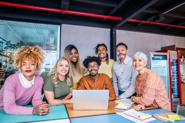 Photographic image of a group of people sitting around a laptop