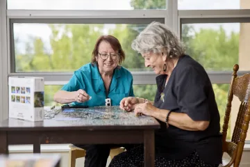 Image of nursing staff and elderly person doing a puzzle.
