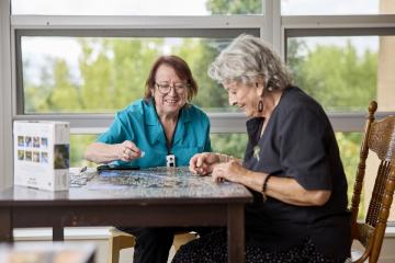 Image of nursing staff and elderly person doing a puzzle.