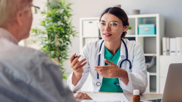 Female doctor wearing glasses talking to a middle aged man over a desk