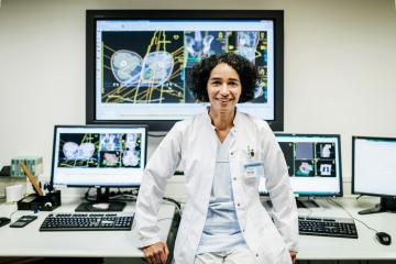 Female scientist stand in front of various screens