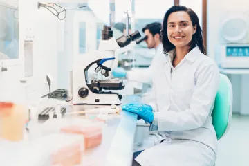 Researcher sitting at a workstation with a microscope
