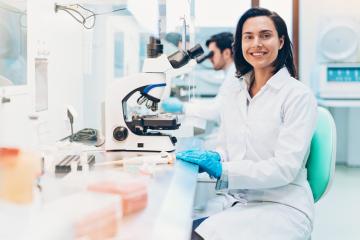 Researcher sitting at a workstation with a microscope