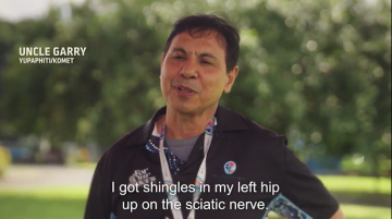 Man in black polo top with a lanyard around his neck being asked about his experience with Shingles