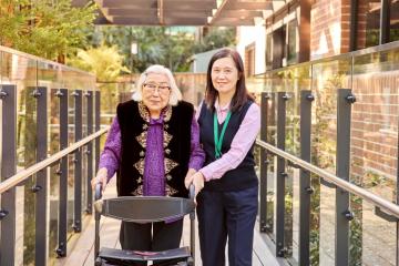 Elderly lady with walker and carer