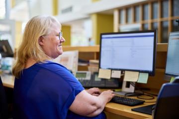 Female office worker typing and viewing desktop screens