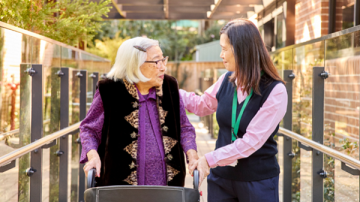 Elderly female with walker and care worker supporting her